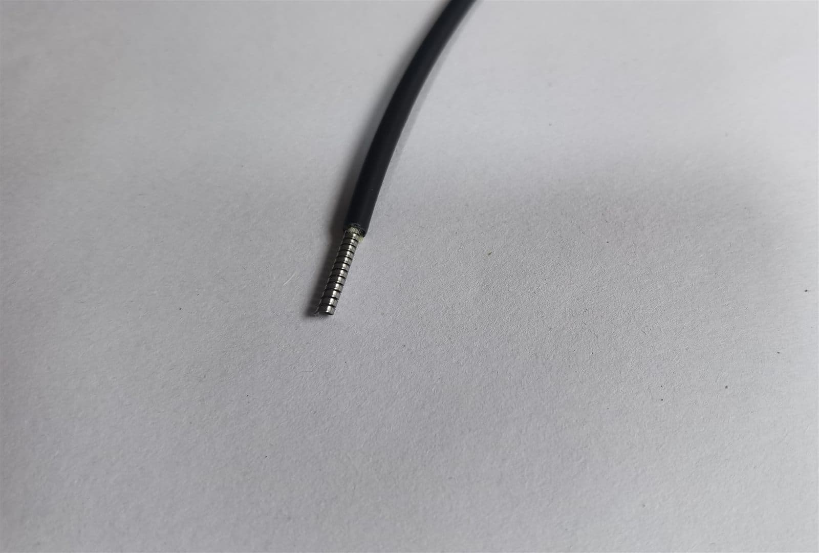 Stripped armored fiber patch cord showing the stainless steel armour layer under the black outer jacket