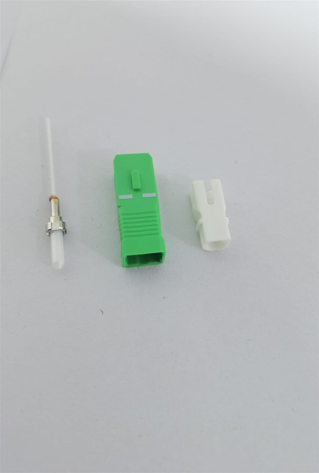 Disassembled fiber connector showing ceramic ferrule, spring, housing and boot parts